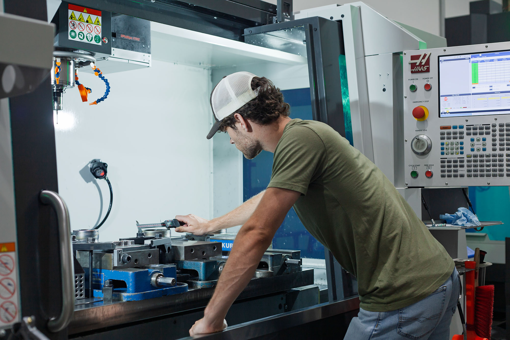 Hybrid Manufacturing—Bearings An engineer leans into a Haas VF5 hybrid system to measure a hybrid manufactured bearing race.